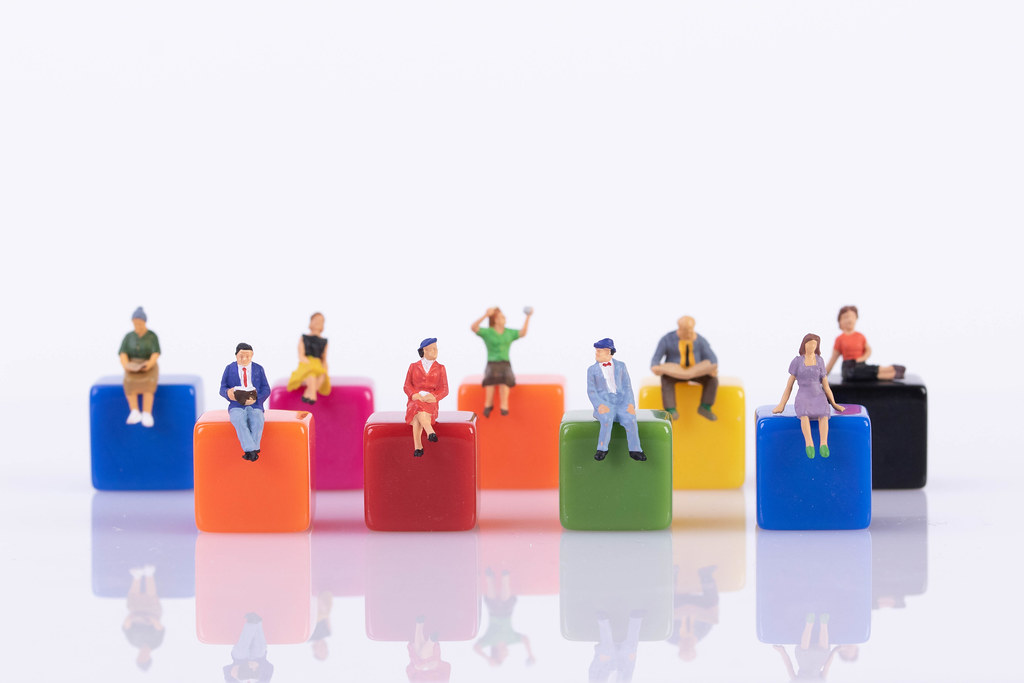 Miniature people sitting on colorful blocks