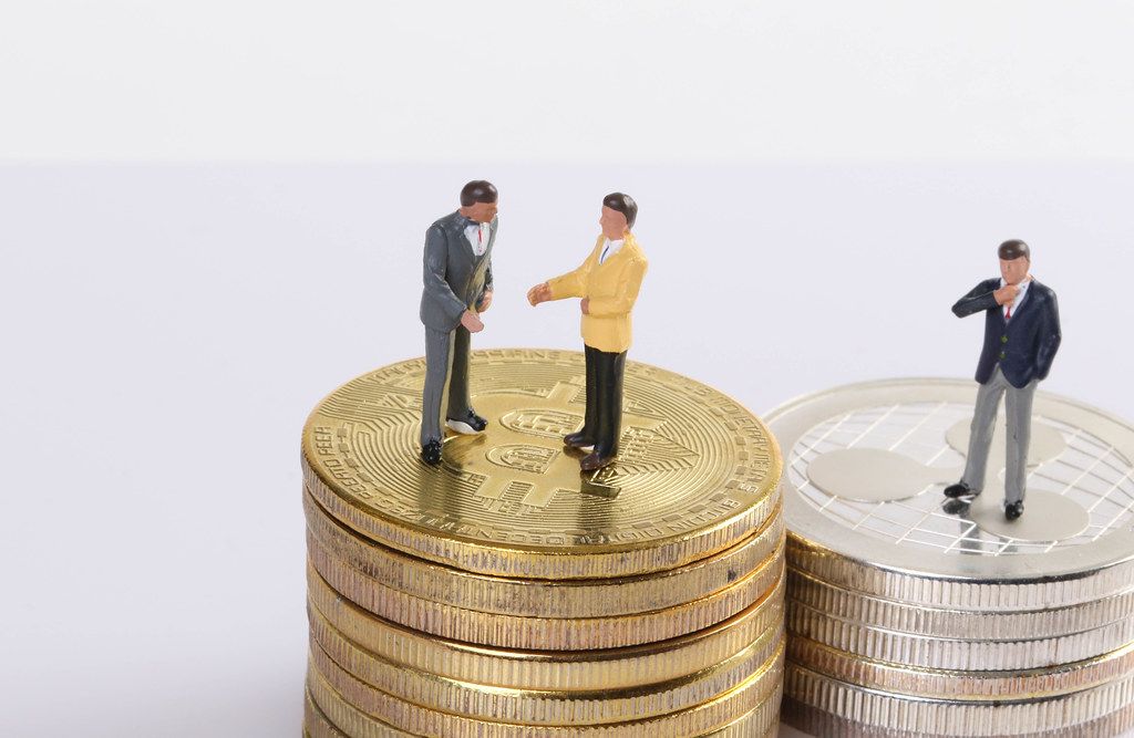 Miniature people standing on coins