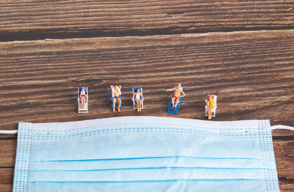 Miniature people wearing swimsuit relaxing near the face mask