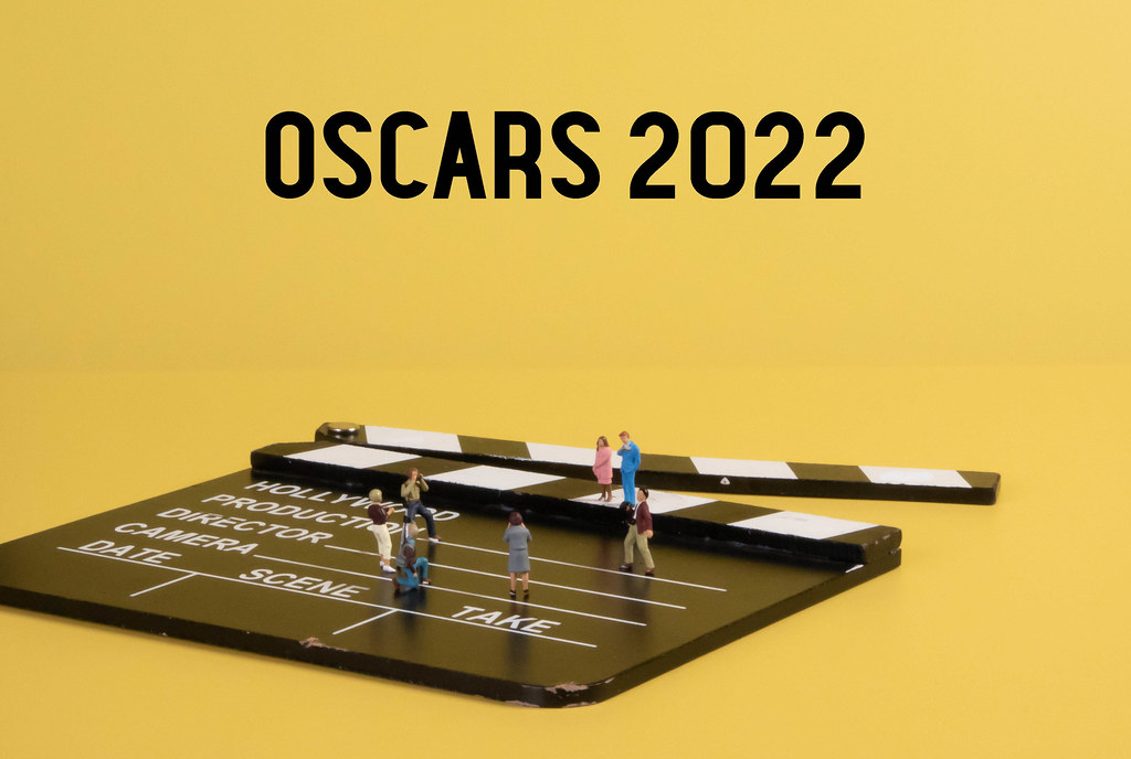 Miniature people with cameras on movie clapper and Oscars 2022 text