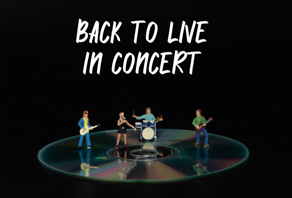 Miniature rock band standing on CD and Back to Live in concert text