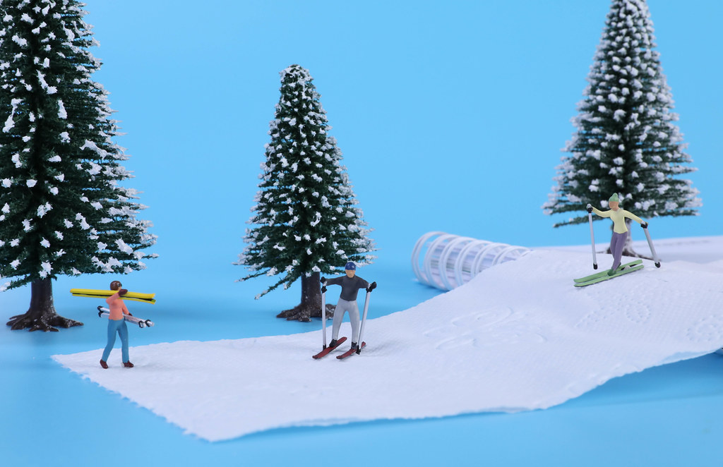 Miniature skiers on snow with blue background