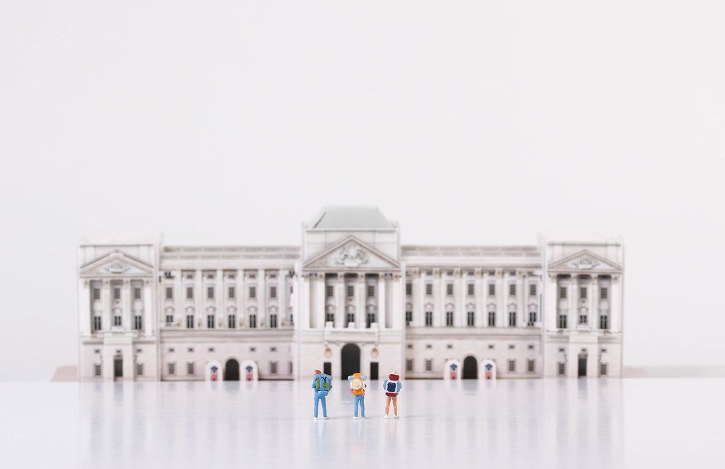 Miniature travelers stading in front of Buckingham Palace