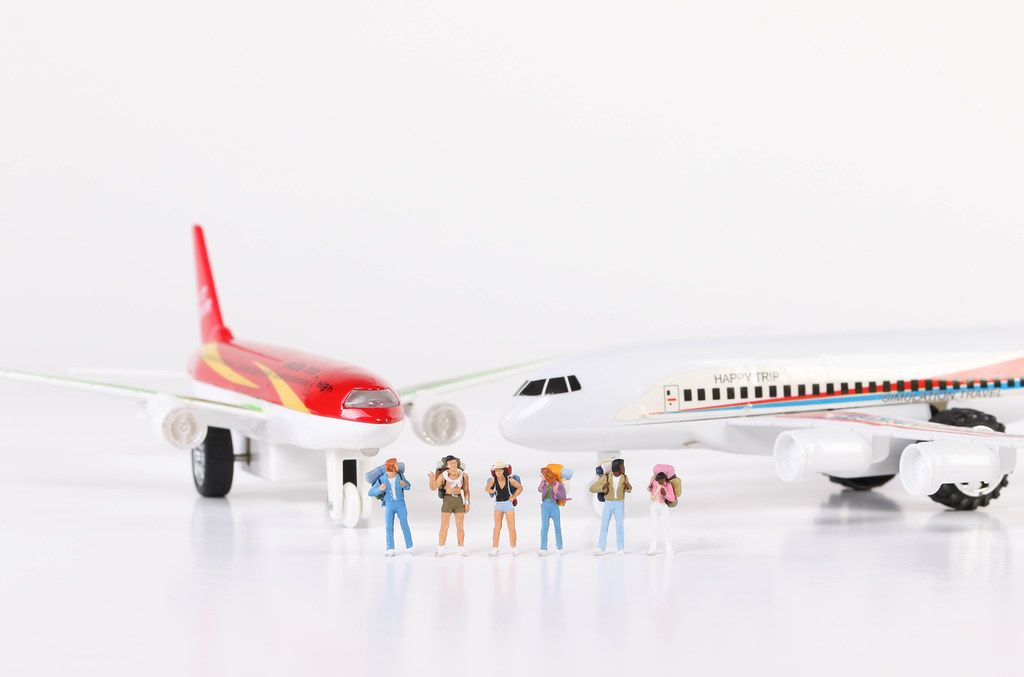 Miniature travelers standing in front of toy airplanes
