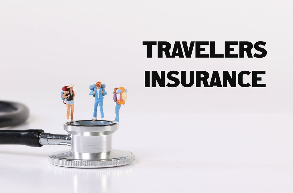 Miniature travelers with stethoscope and Travel Insurance text