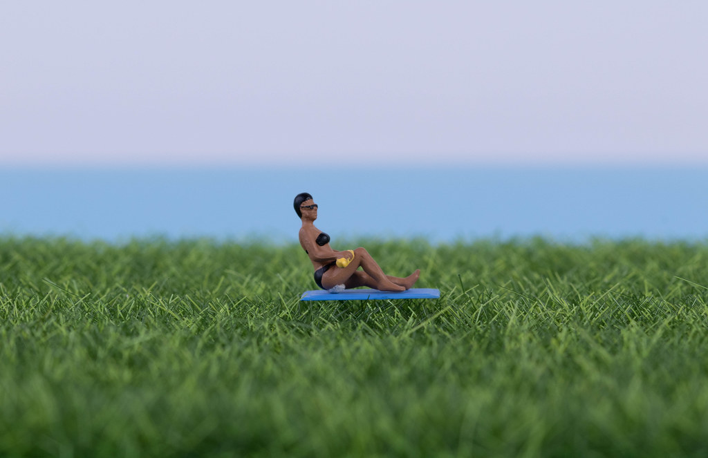 Miniature women relaxing on green grass