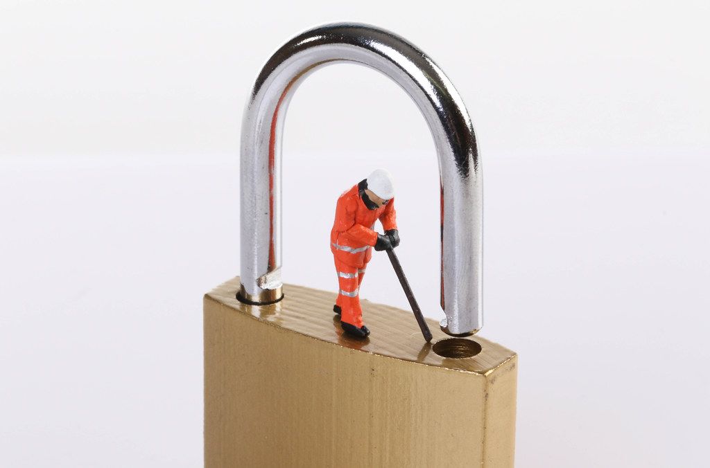 Miniature worker trying to unlock the padlock