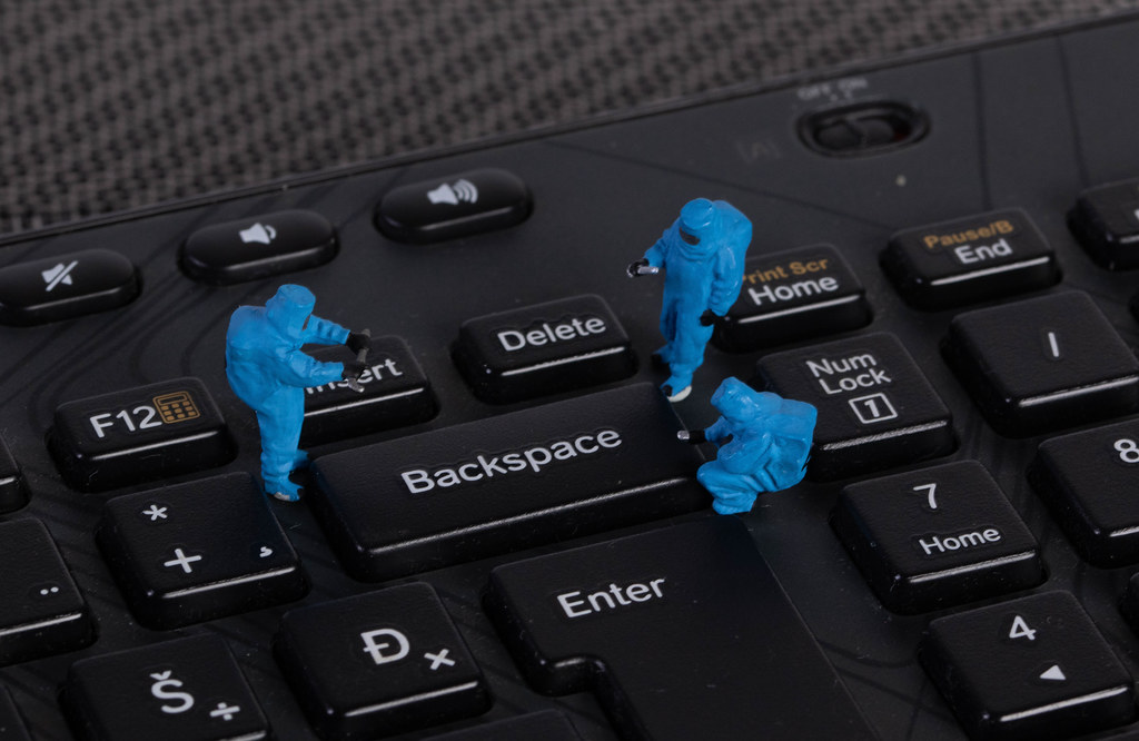 Miniature workers in protective clothes on a keyboard with Backspace button