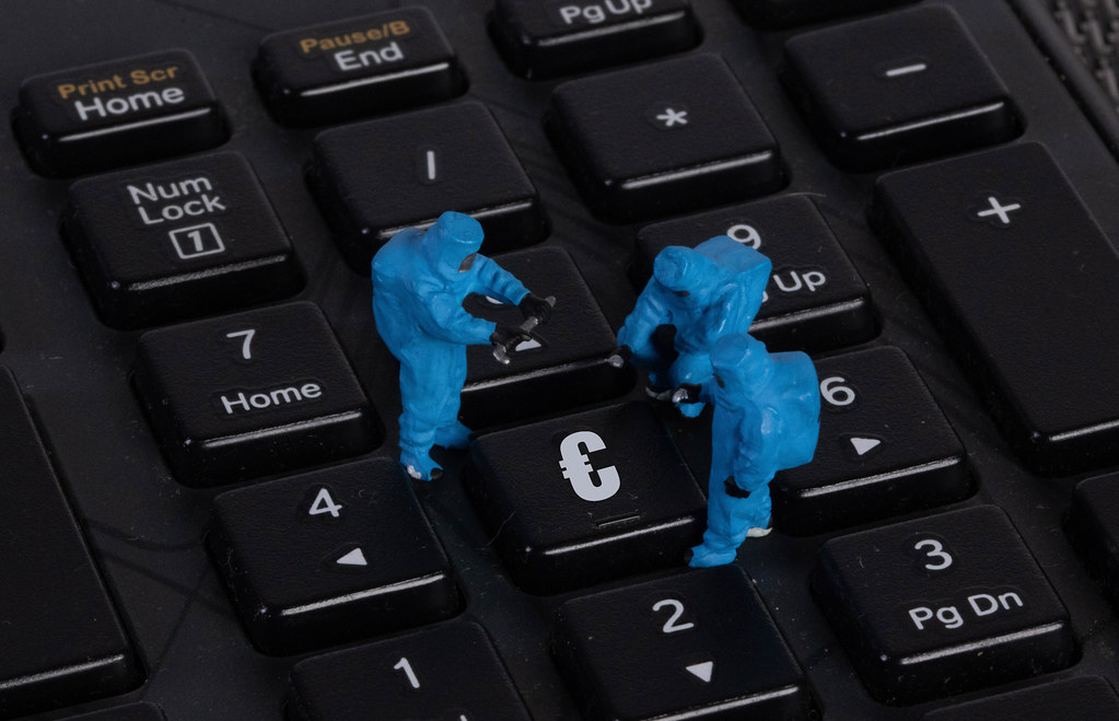 Miniature workers in protective clothes on a keyboard with Euro button