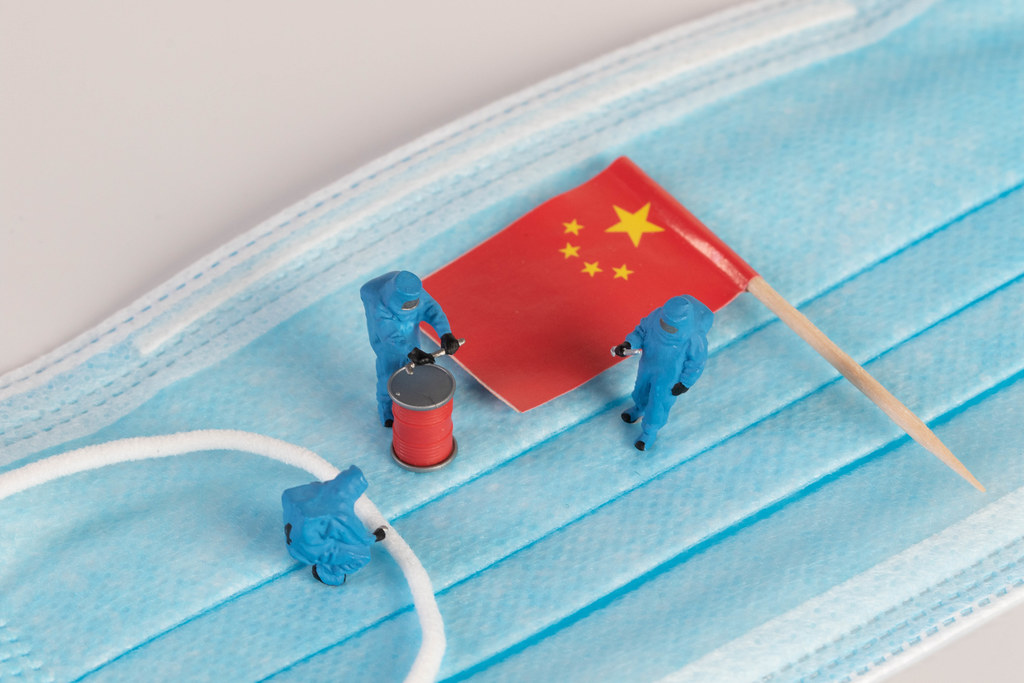 Miniature workers in protective clothes on a medical mask with flag of China