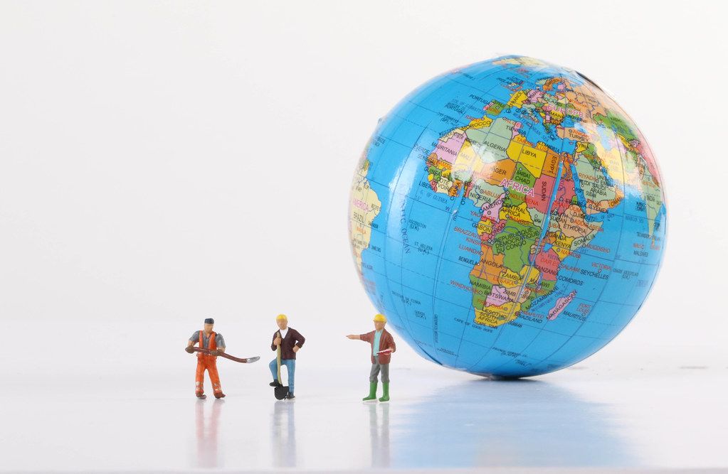 Miniature workers with globe on white background