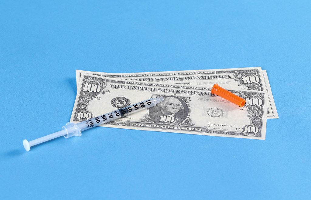 Money and syringe isolated on blue