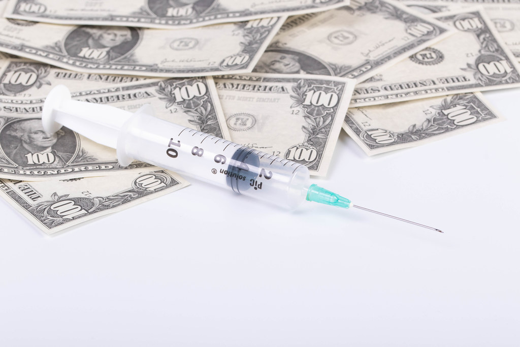 Money and syringe on white background