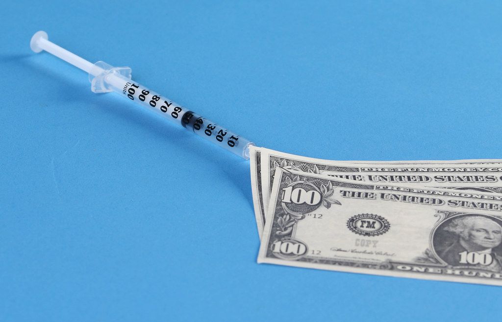 Money and syringe with blue background