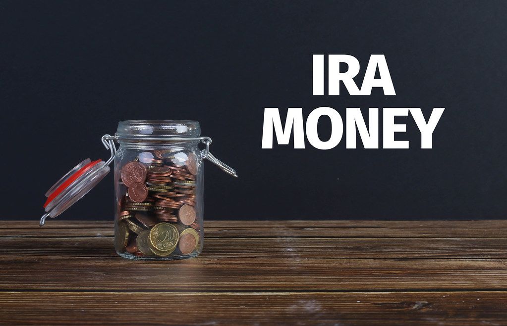 Money jar on wooden table with IRA Money text