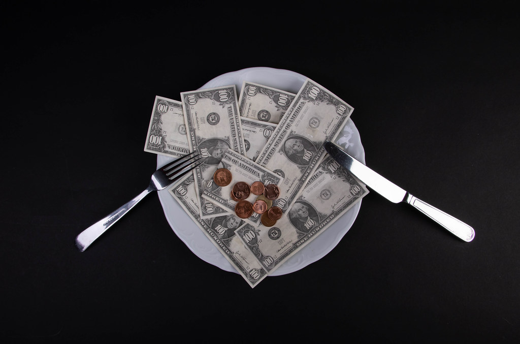 Money lying on the plate with fork and knife