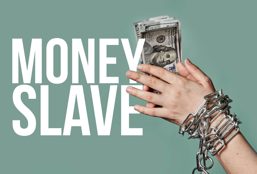 Money slave - business person hands chained holding money