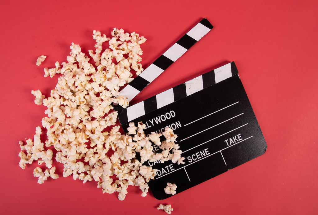 Movie clapper and popcorn on red background