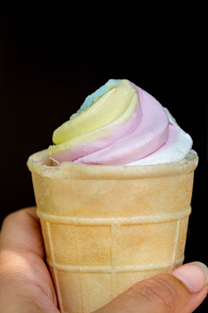 Multicolored ice cream in a waffle cup in a female hand, close-up