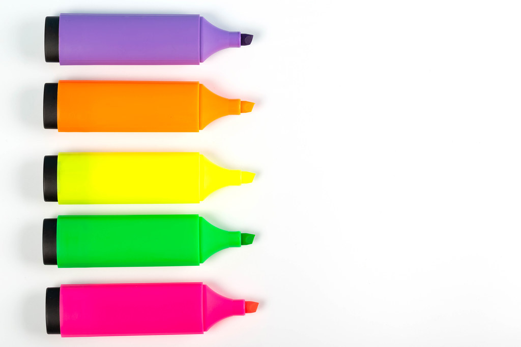 Multicolored markers on white background with free space, top view