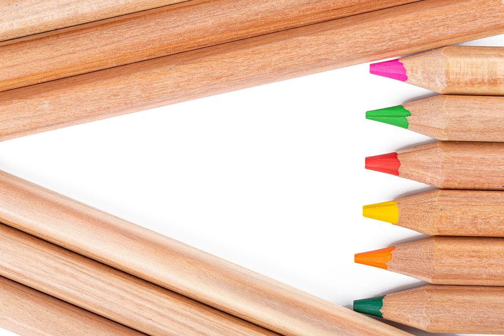 Multicolored pencils background with white free triangle
