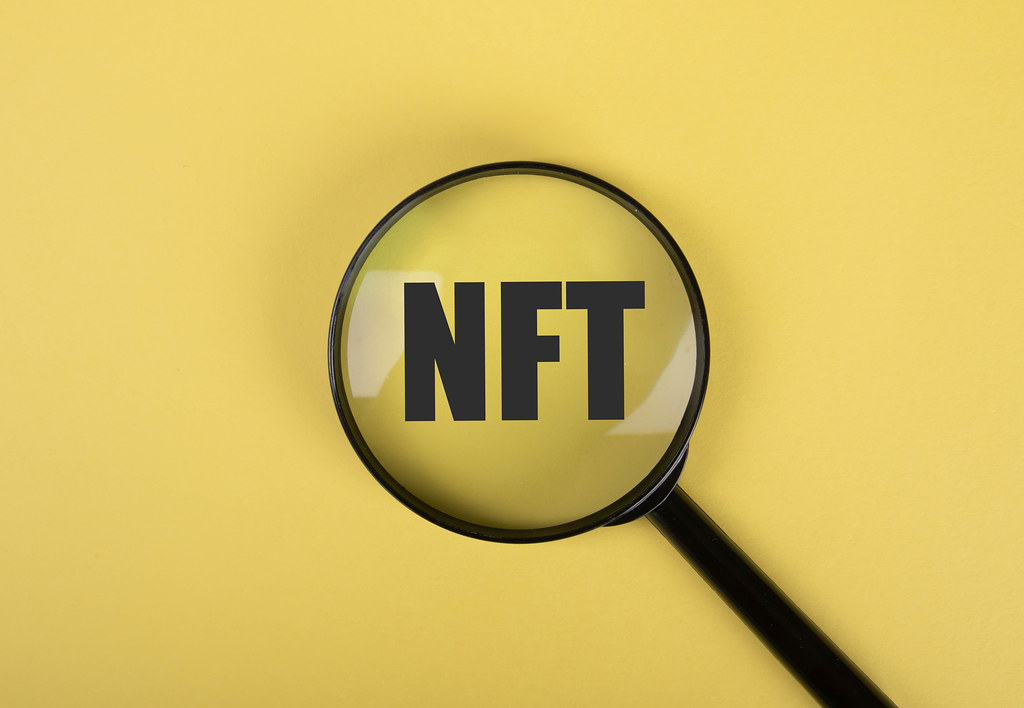 NFT text and magnifying glass on yellow background