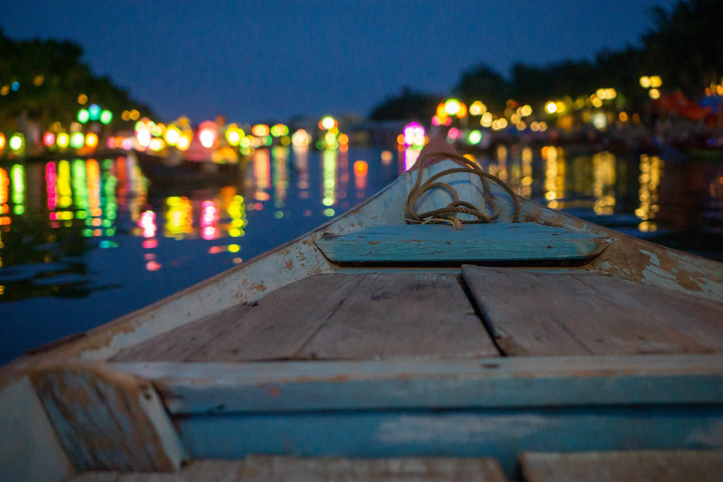 Night Photo from a Wooden Tourist Boat with Bright Lights reflecting in Thu Bon River in Hoi An, Vietnam