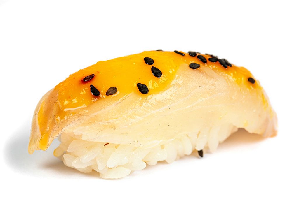 Nigiri with sea bass fillet and mango sauce on a white background