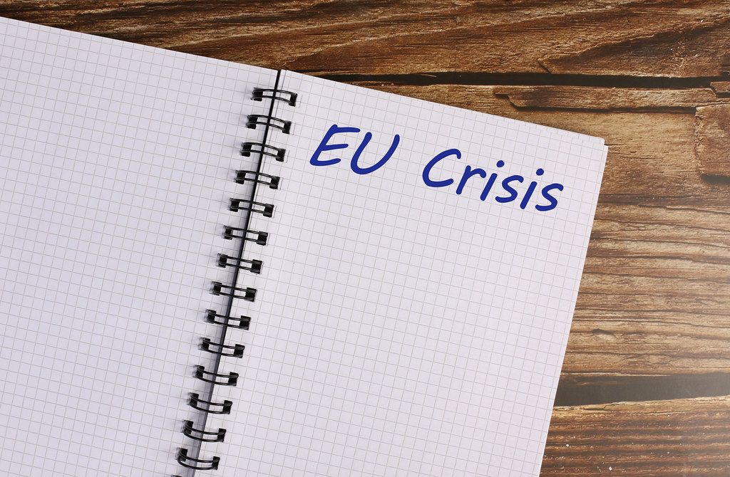 Notebook with EU Crisis text on a wooden table