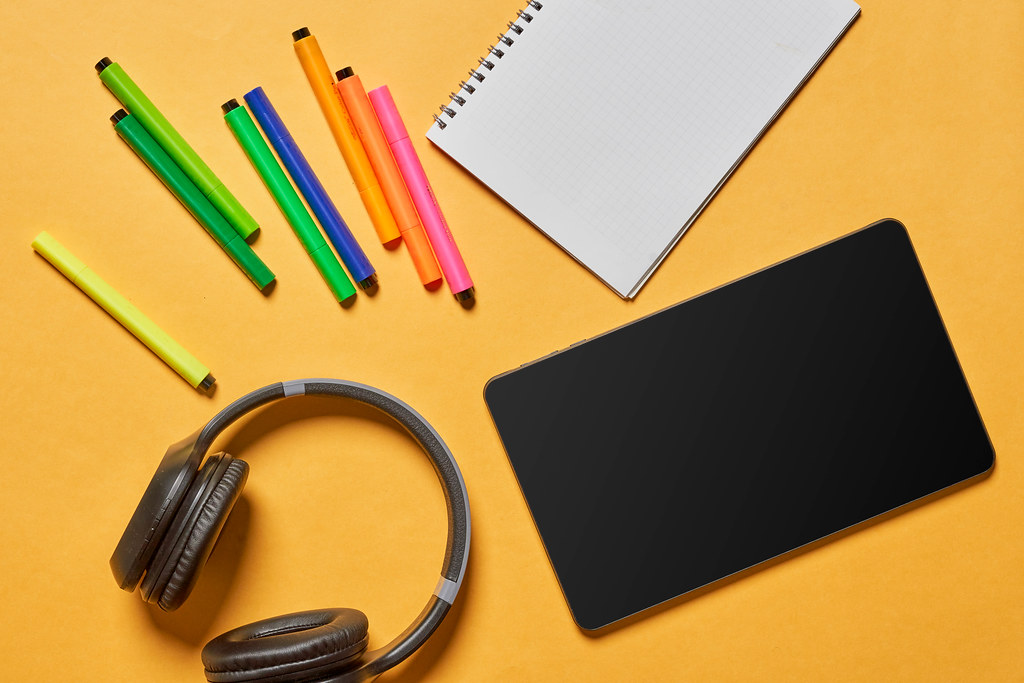 Notepad, colorful pens, headphones and tablet with empty screen