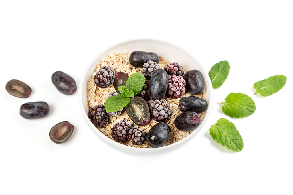 Oatmeal with blueberries, grapes and mint on a white background