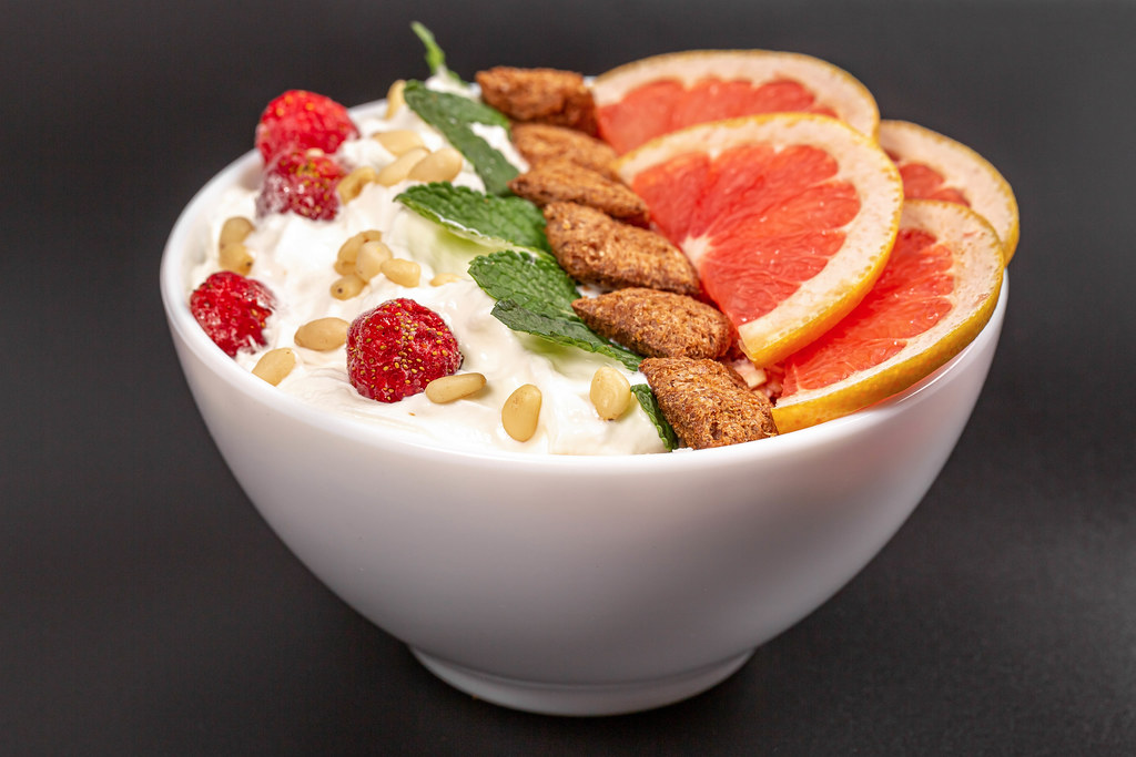 Oatmeal with pine nuts and grapefruit pieces in a bowl on a black background