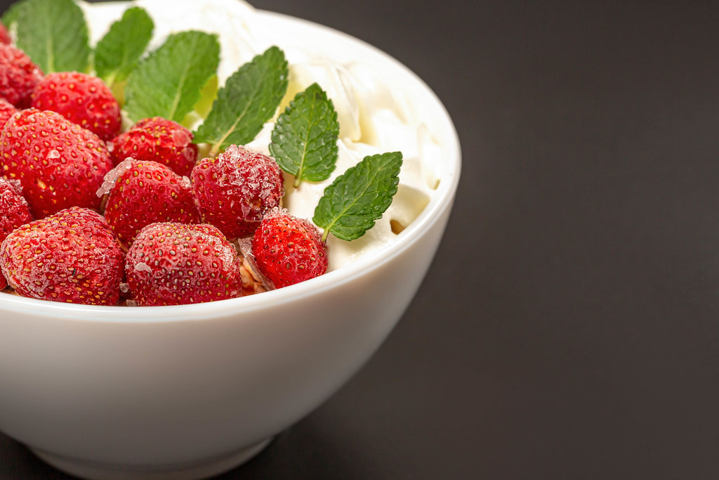Oatmeal with strawberries, whipped cream and mint leaves, close-up