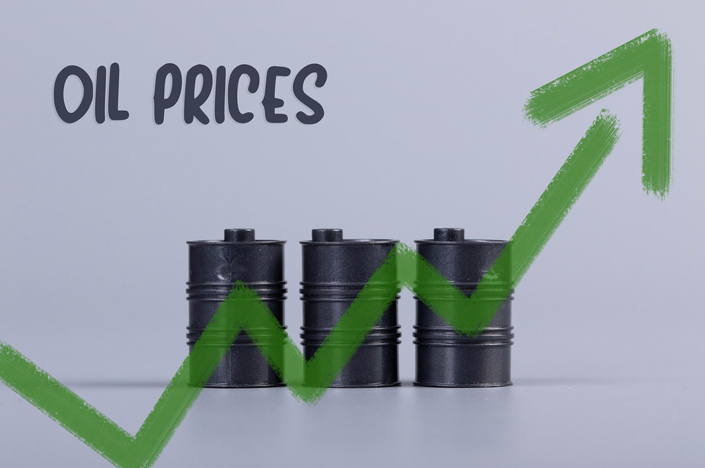 Oil barrels with green up chart and Oil prices text on grey background