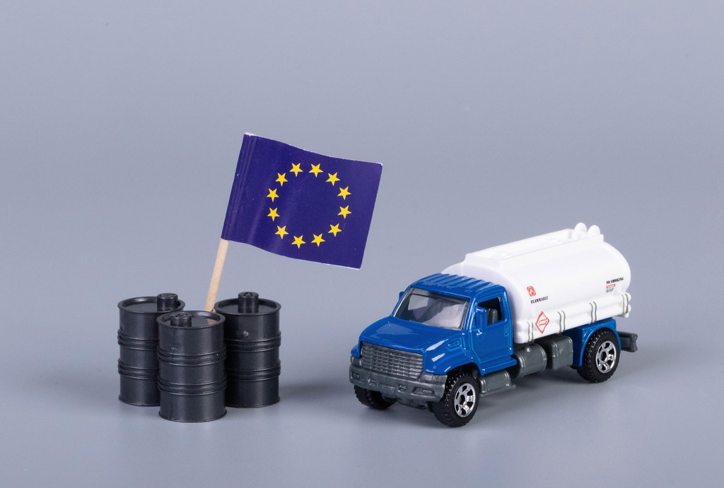 Oil truck and oil barrels with flag of European Union on grey background