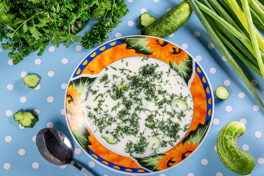 Okroshka in a plate with cucumber and herbs on a table. Russian, ukrainian and georgian cuisine