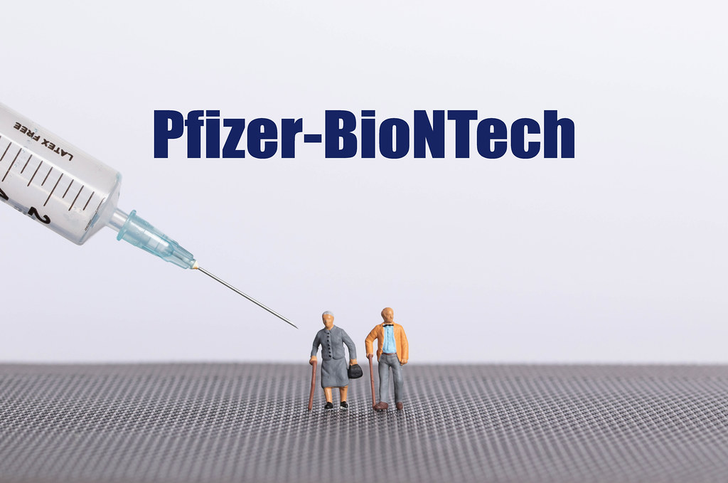 Older couple with syringe and Pfizer-BioNTech text