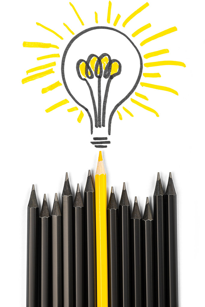One yellow pencil with a light bulb among black ones, business concept