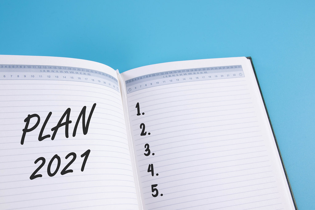 Open notebook with 2021 Plans list on blue background