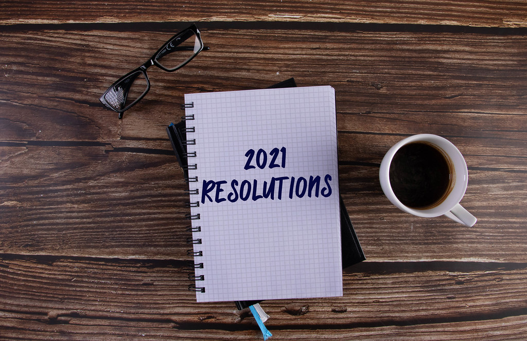 Open notebook with 2021 Resolutions text on wooden table