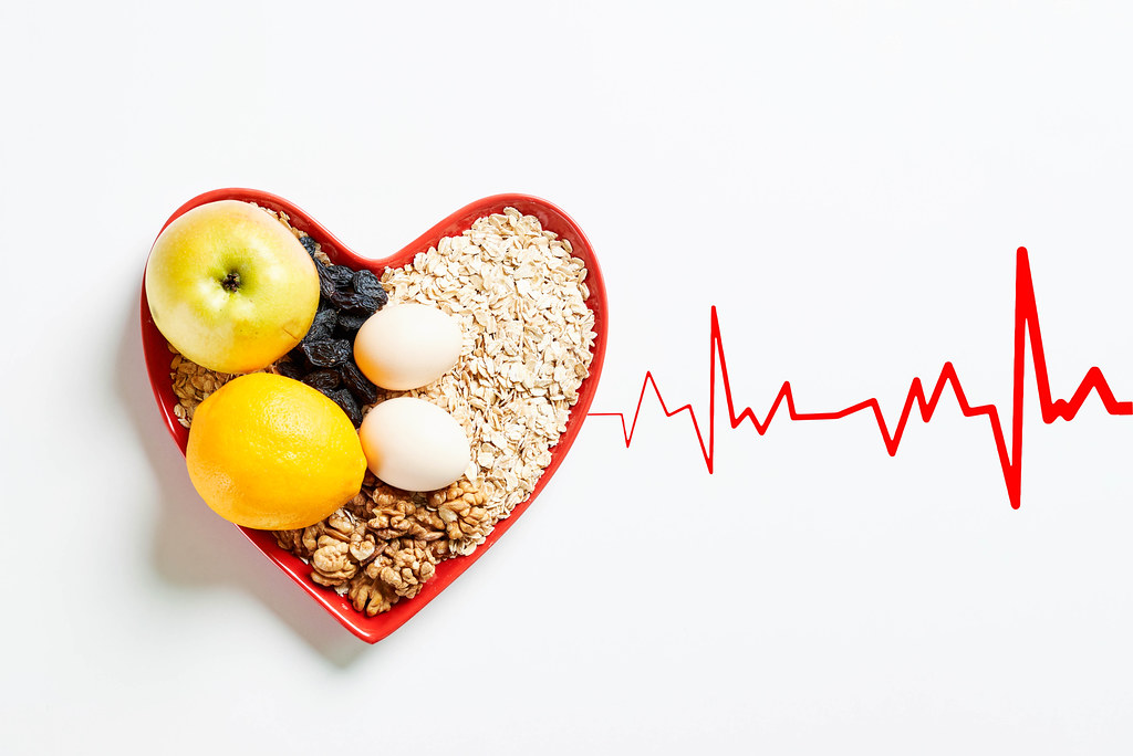 Organic fruits, cereals and nuts in heart shape plate with a heartbeat
