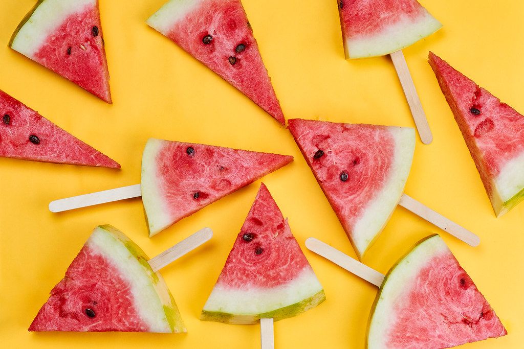 Organic watermelon slices with sticks on bright yellow background