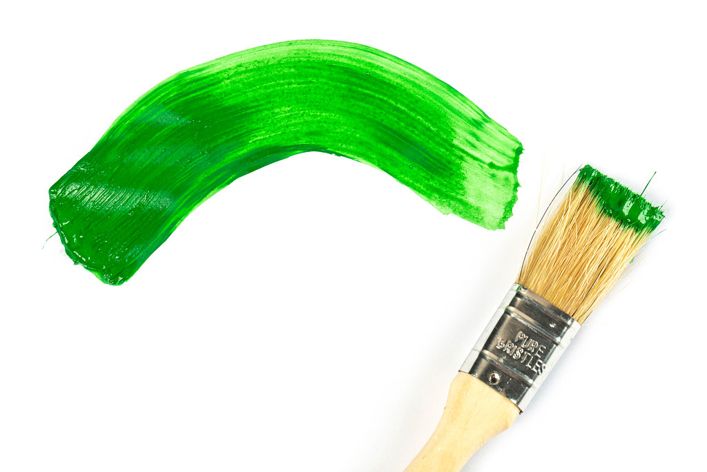Paint brush with wooden handle and dab of green paint