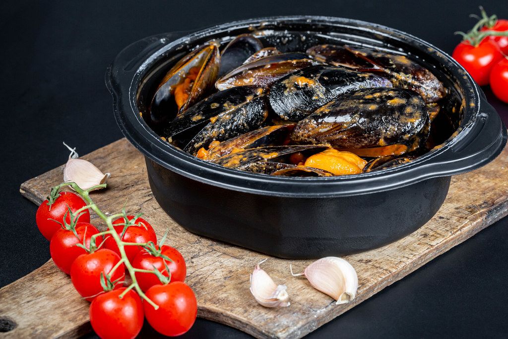 Pan with delicious mussels in garlic-tomato sauce