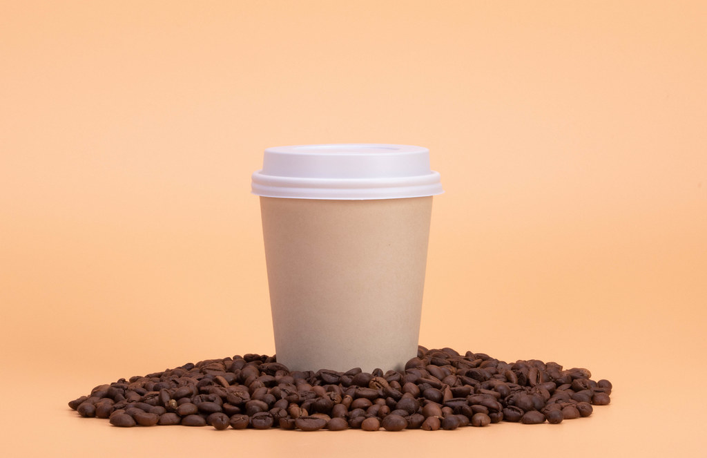 Paper cup of coffee and coffee beans