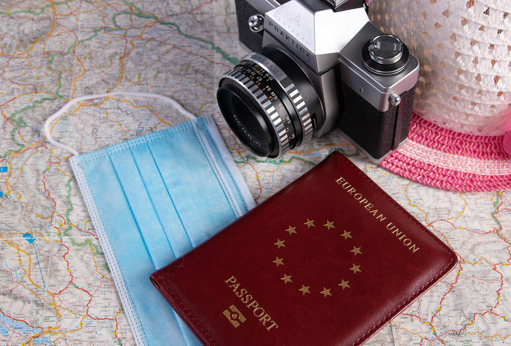 Passport, medical face mask and vintage camera on a map