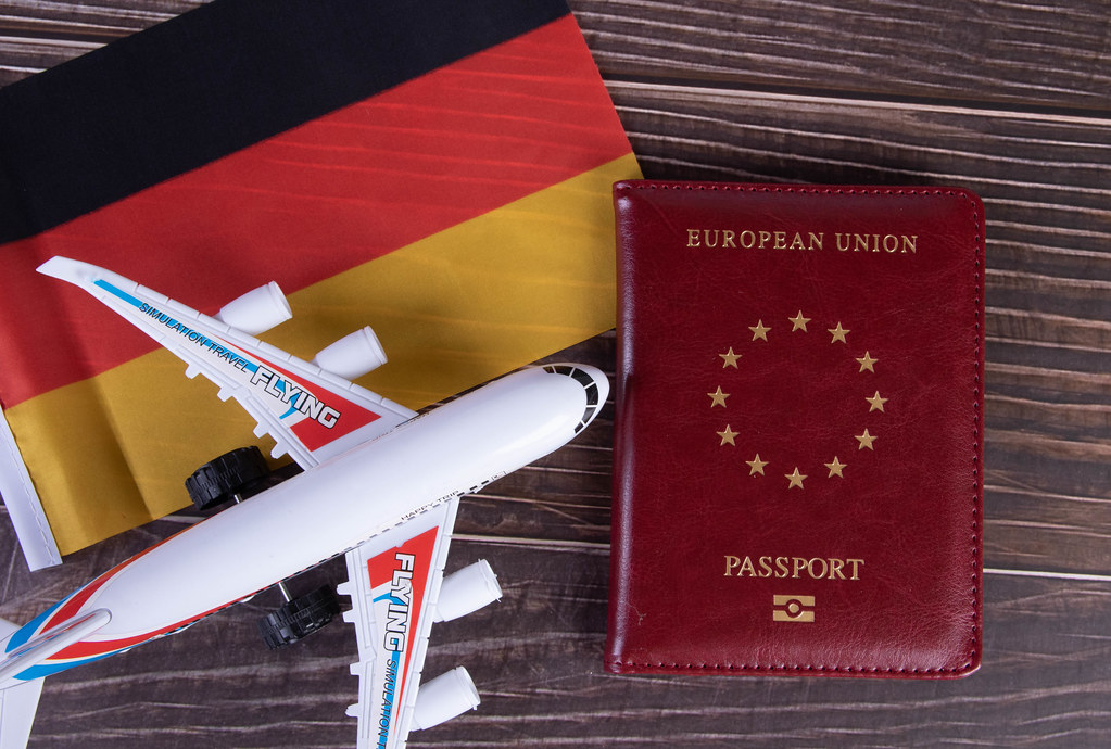Passport, miniature airplane and flag of Germany on wooden table