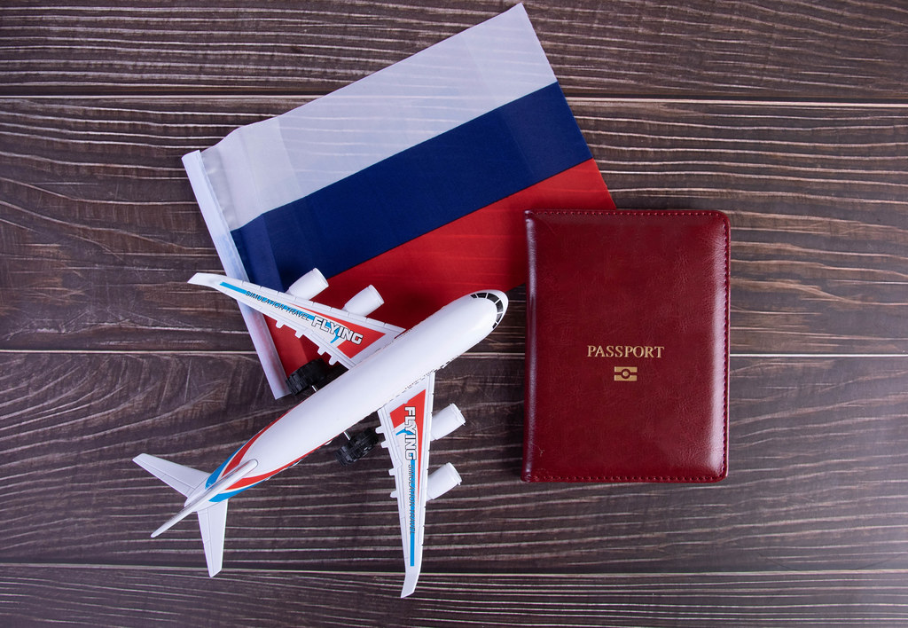Passport, miniature airplane and flag of Russia on wooden table