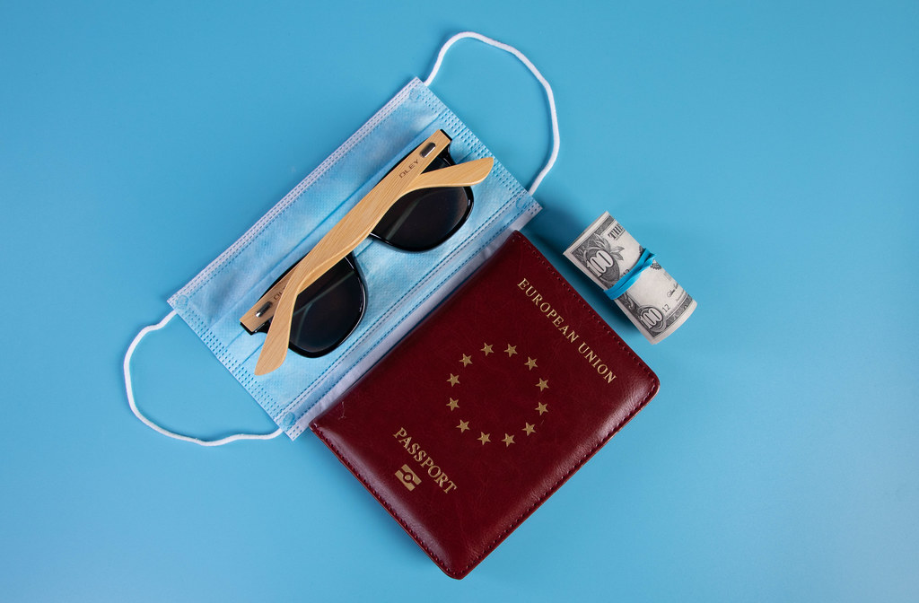 Passport with face mask and sunglasses on blue background