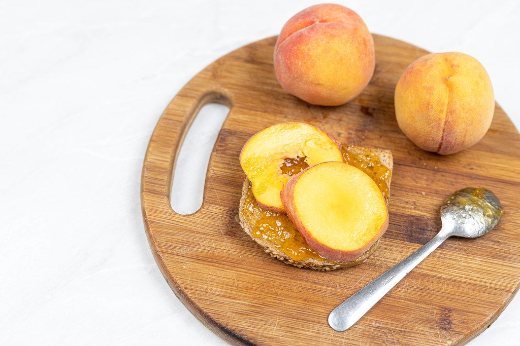 Peaches and Peach Jam spread on the bread on the wooden board